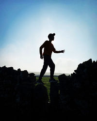 Rear view of man standing on rock against sky