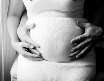 Midsection of pregnant woman with white dress