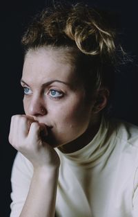 Portrait of young woman against black background