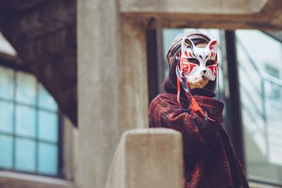 Midsection of woman wearing mask against window