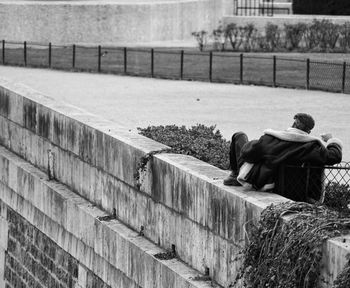 Man sitting on surrounding wall