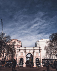 Low angle view of buildings against cloudy sky