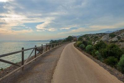 Empty road by sea against sky