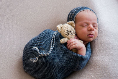 Newborn in a crib in a blue winding and cap