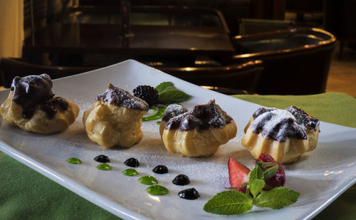 Close-up of profiteroles garnished with fruits in tray on table