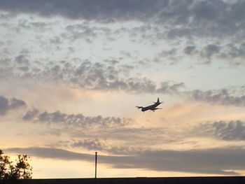 Low angle view of airplane flying against cloudy sky