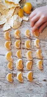 Cropped hand arranging orange fruits on wooden table