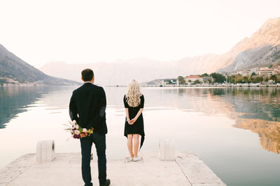 Rear view of people looking at mountains against sky