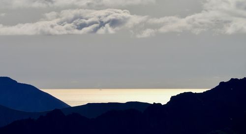 Scenic view of silhouette mountain by sea against sky