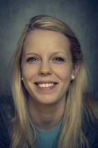 Close-up portrait of beautiful woman against gray wall