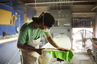 Man working on surfboard in workshop