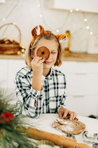 A cheerful girl hides her eyes behind christmas cookies. preparation for the holidays