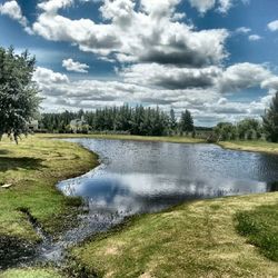 Scenic view of river against cloudy sky