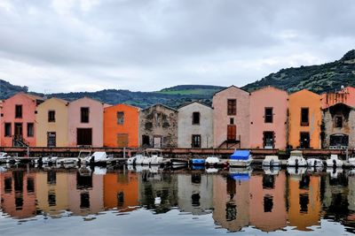 Houses by canal against sky in city