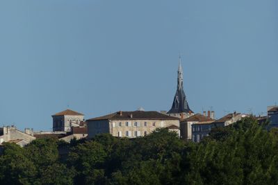 Trees and buildings against clear blue sky