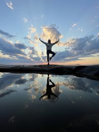 Silhouette man standing in lake against sky during sunset