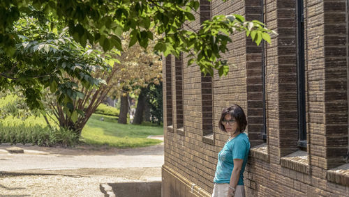 Woman standing by tree against plants