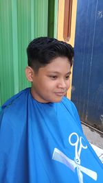 Portrait of boy standing against blue wall