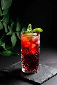 Glass of alcoholic coctail with ice on black background