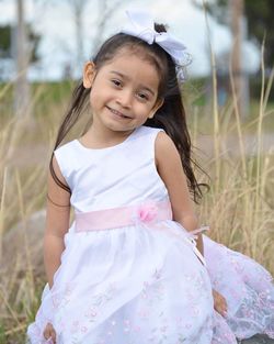 Portrait of smiling girl standing on grassy field