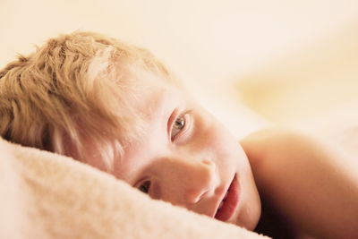 Close-up of thoughtful boy lying on bed at home