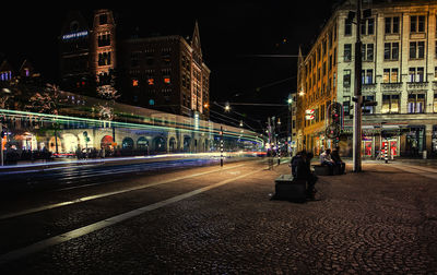 Light trails on road amidst buildings in city at night