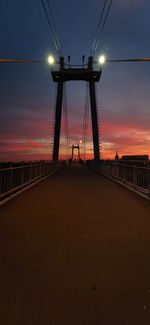 Bridge over road against sky during sunset