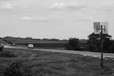 Scenic view of road amidst field against sky