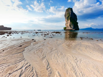 Rock formations on beach against sky