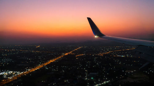 Aerial view of illuminated city against sky at sunset