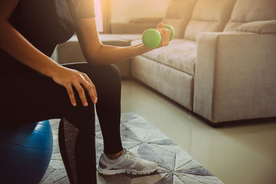 Low section of woman sitting on sofa at home