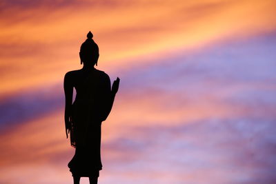 Silhouette buddha statue against sky during sunset