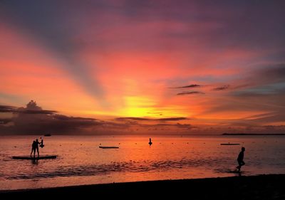 Silhouette people at beach against sky during sunset