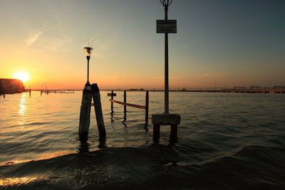 Silhouette man standing by sea against sky during sunset