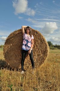 Full length of woman standing by hay bale