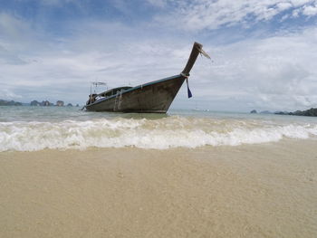 Close-up of wave with boat anchored at beach