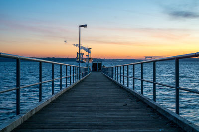 Pier over sea against sky during sunset