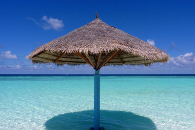 Lifeguard hut on sea against blue sky