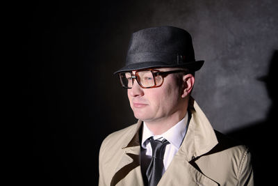 Close-up of man wearing hat and jacket against wall