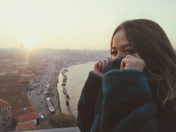 Young woman in city against clear sky during sunset