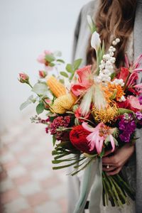 Midsection of woman by red flowering plant