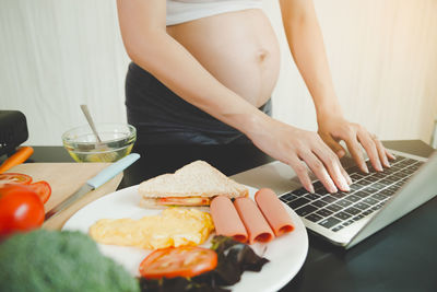 Midsection of woman using laptop on table