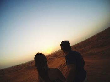 Silhouette couple against clear sky during sunset