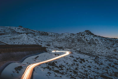 Aerial view of snowcapped mountains against clear blue sky at night