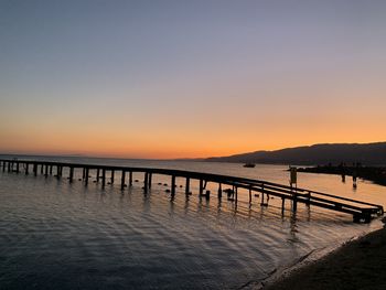 Pier over sea against clear sky during sunset