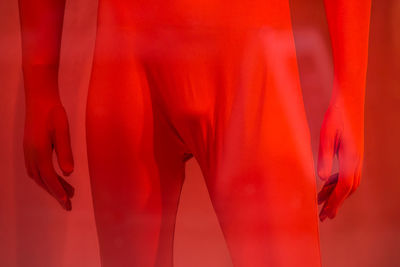 Midsection of man in costume standing against red background