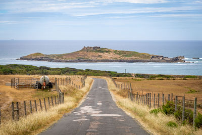 Scenic view of road by sea against sky