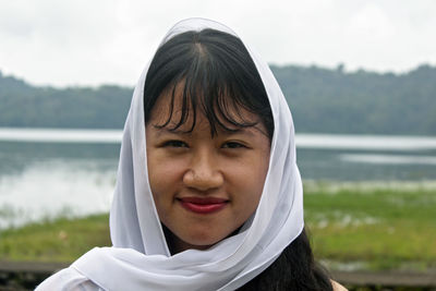 Portrait of smiling young woman against lake