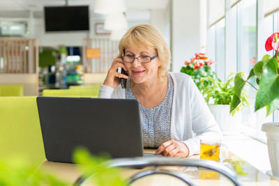 Woman using mobile phone while sitting on table