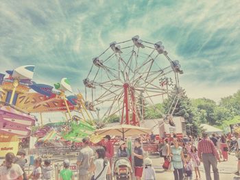 Low angle view of ferris wheel against cloudy sky